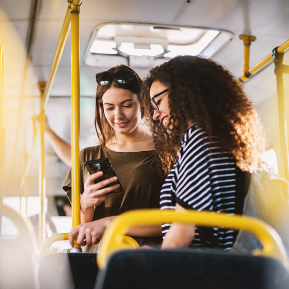 Service Zwei Frauen stehen im Bus und schauen auf ein Smartphone
